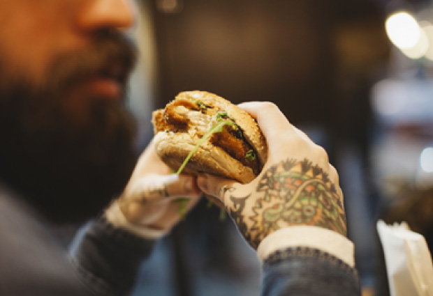 Tattooed hands with burger